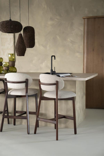 Barkruk Mikky taupe stof bruin eikenhout magazijn leegverkoop in een interieur