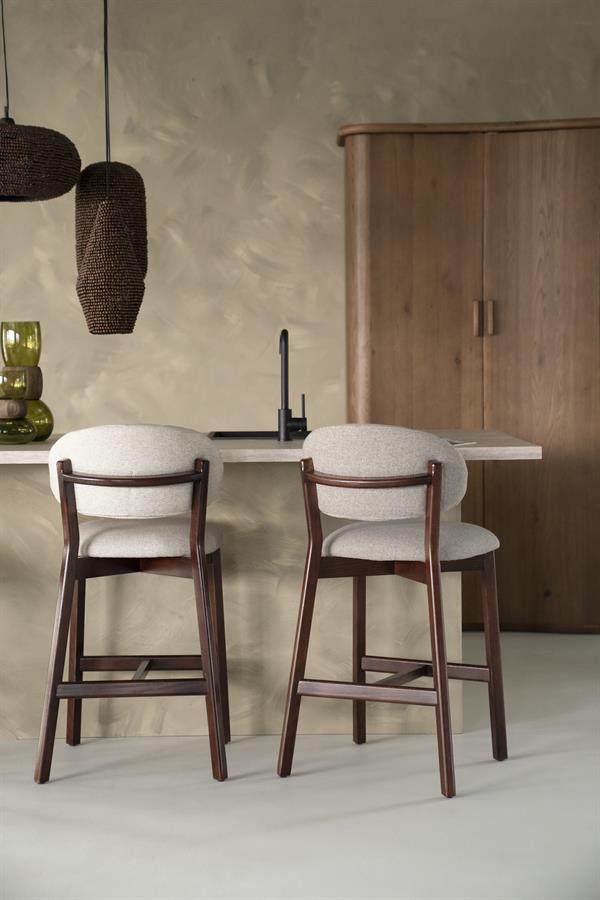 Barkruk Mikky taupe stof bruin eikenhout magazijn leegverkoop in een interieur