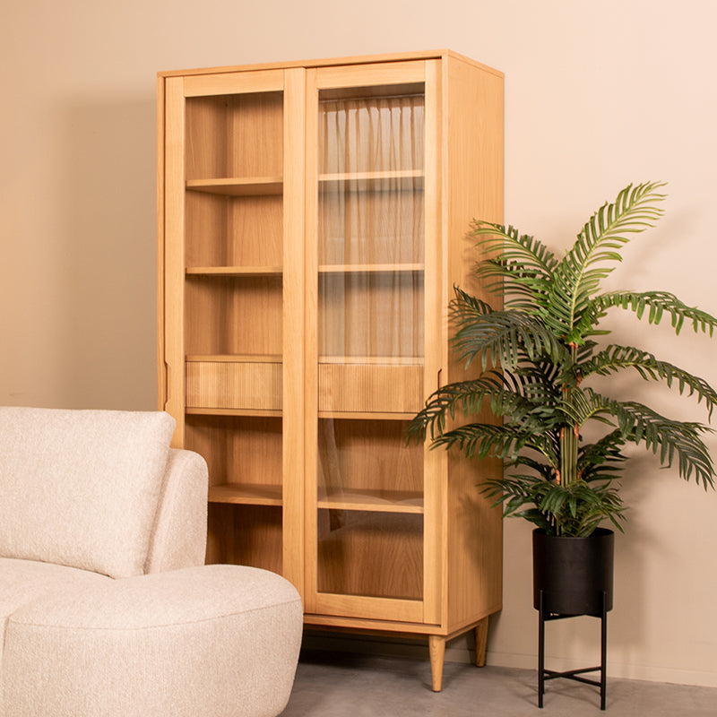 Vitrinekast Jule naturel eikenhout, schuin vooraanzicht in een interieur