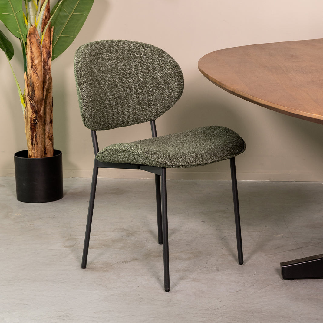 Eetkamerstoel Senn groen bouclé, schuin vooraanzicht in een interieur